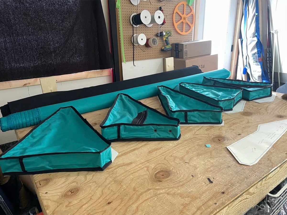 Teal frame bag panels and paper pattern templates on the workshop bench in Canmore