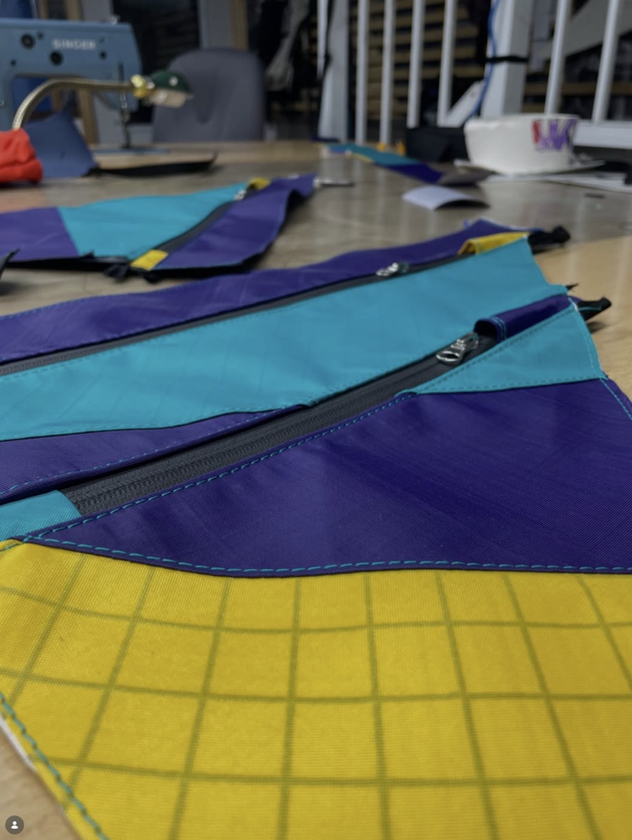 Close view of sewn purple, teal and yellow ripstop panels with a zip