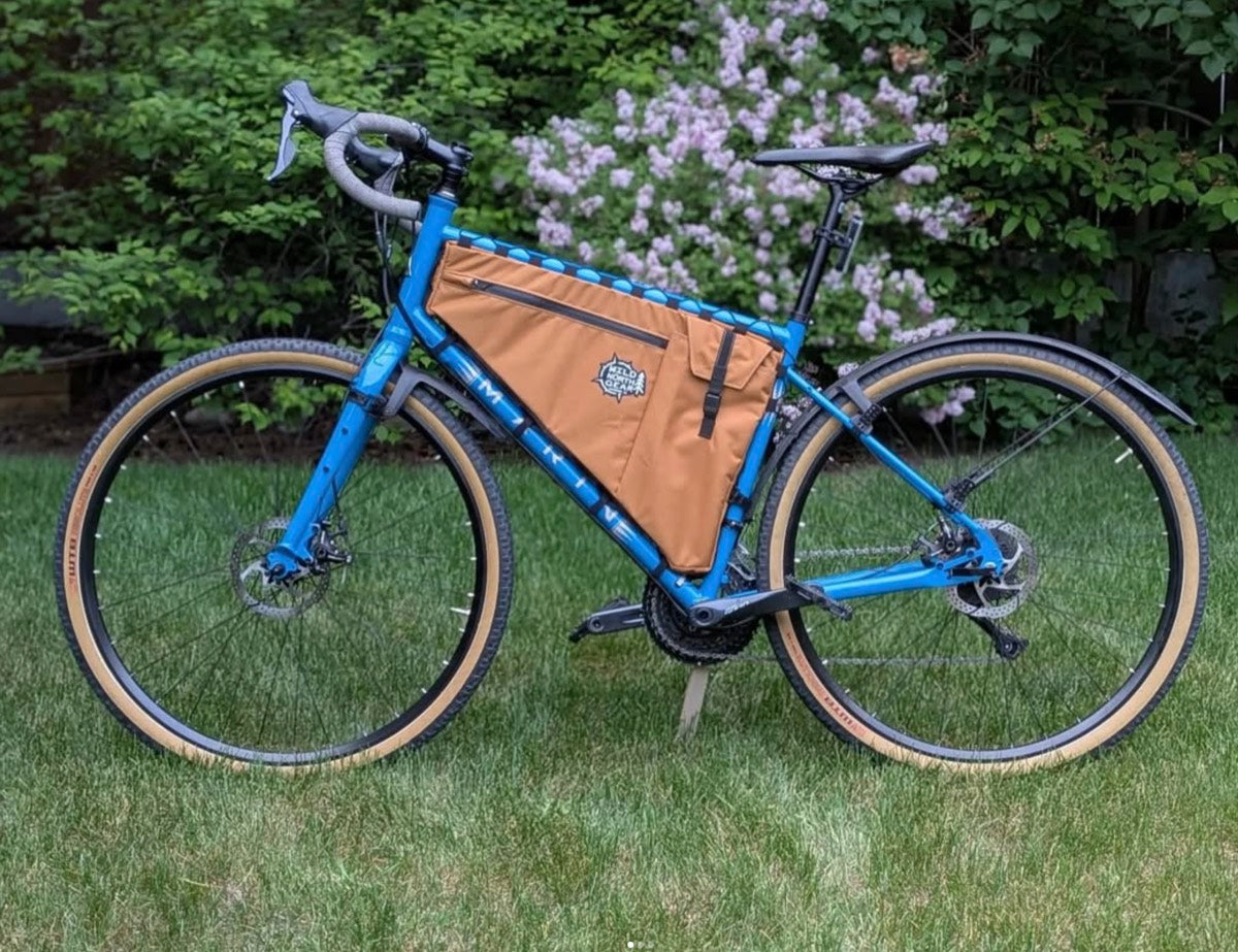 Tan custom frame bag fitted to a blue gravel bike